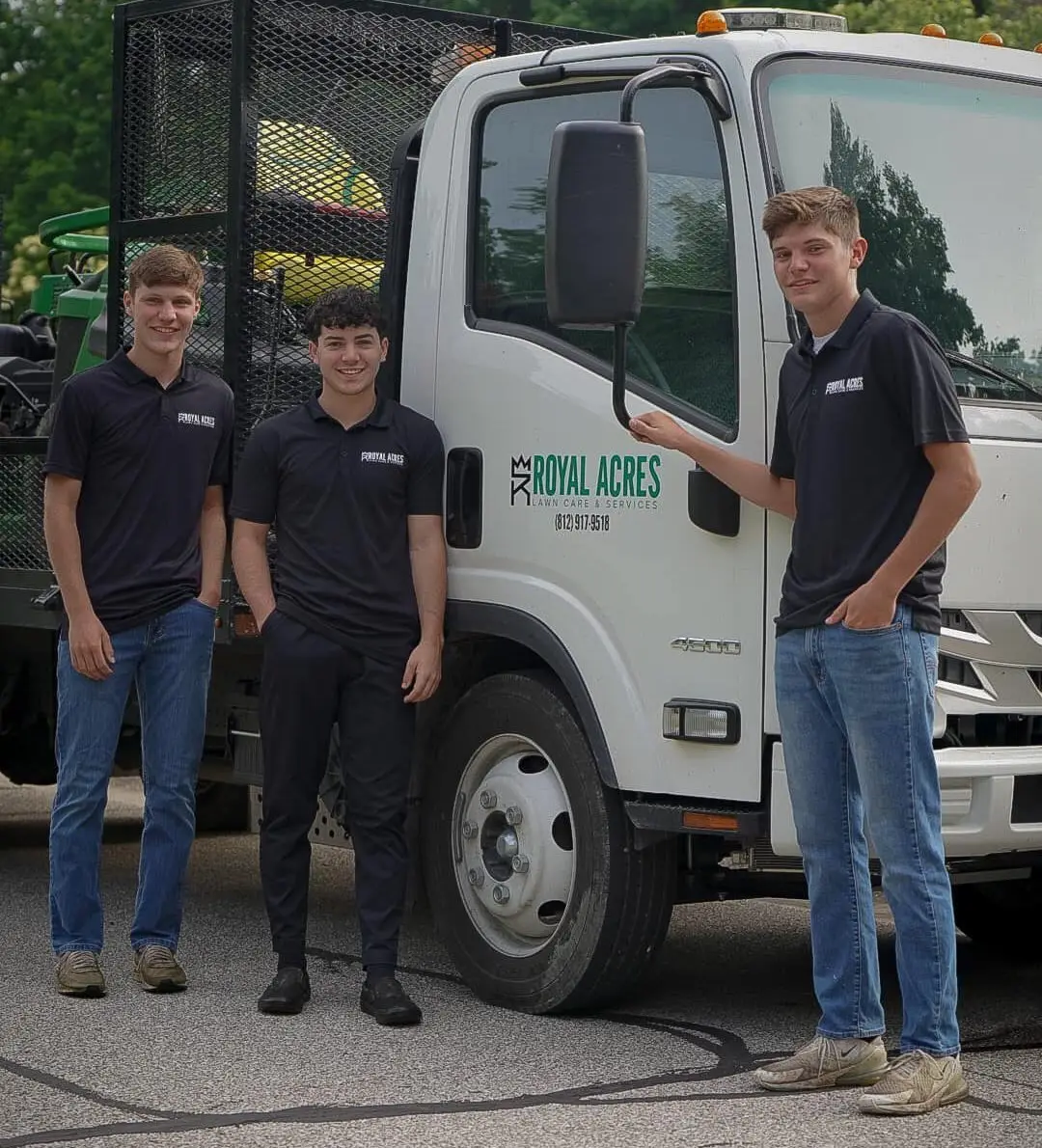 Three of the crew in company polos beside the Royal Acres truck
