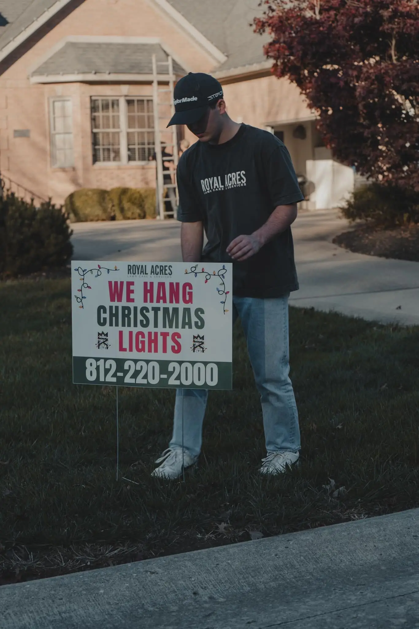 A crew member setting a “We hang Christmas lights” yard sign