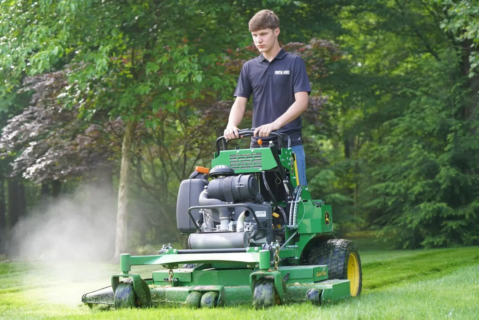Mowing in summer on a stand-on mower, clippings in the air