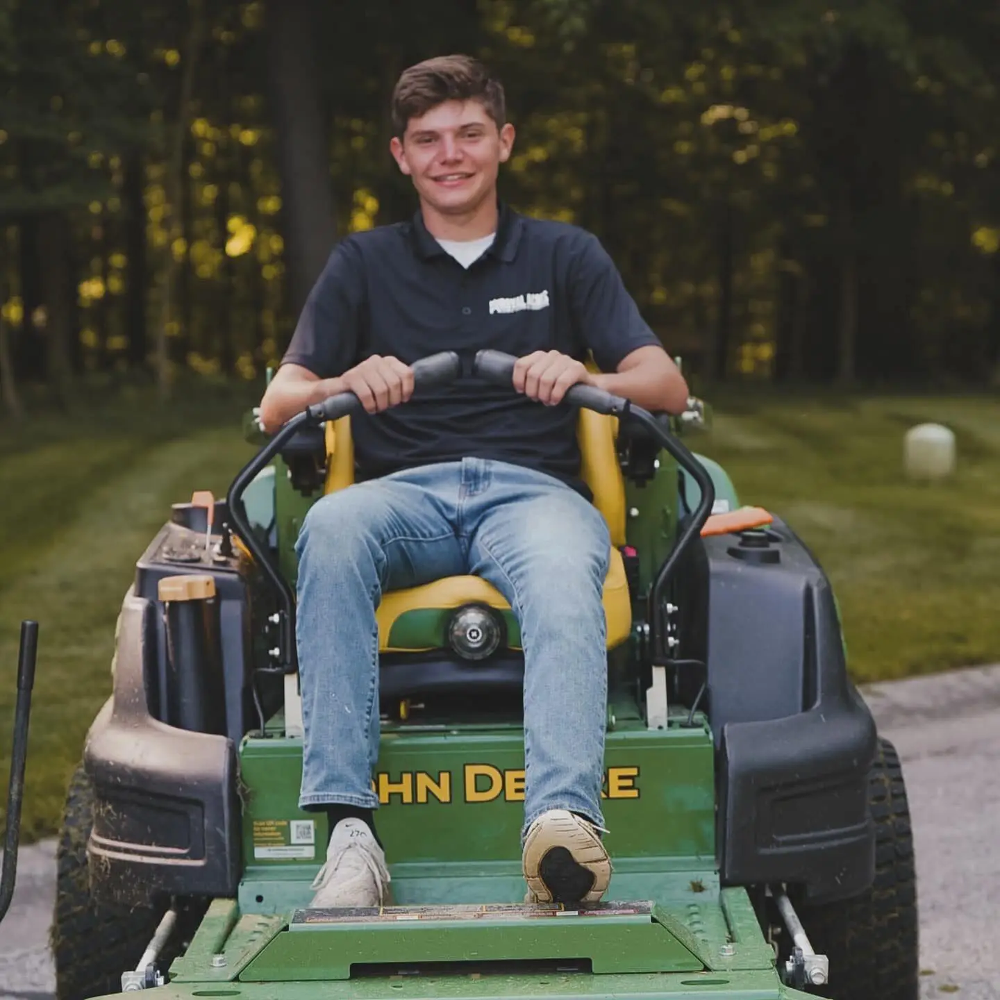 A smiling crew member on a zero-turn mower