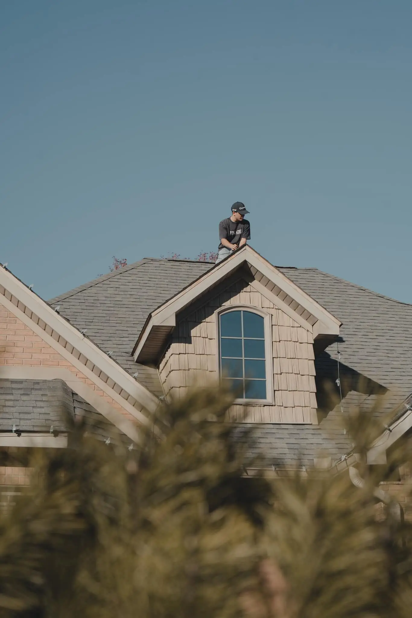 A crew member at a roof peak, seen from the street