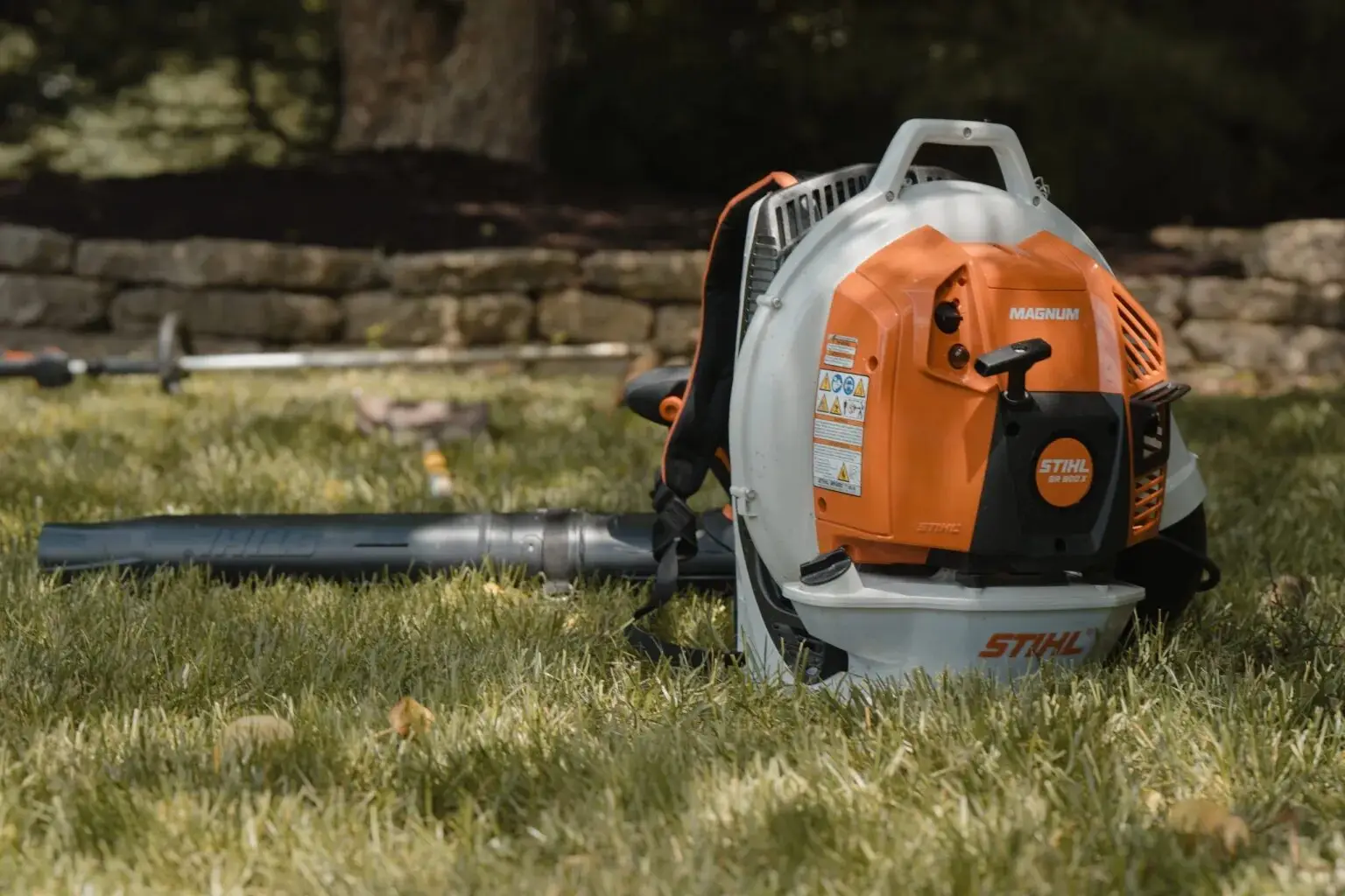 A backpack leaf blower resting on the grass