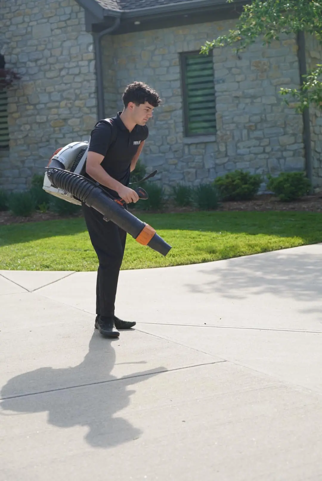 A crew member blowing clippings off a driveway
