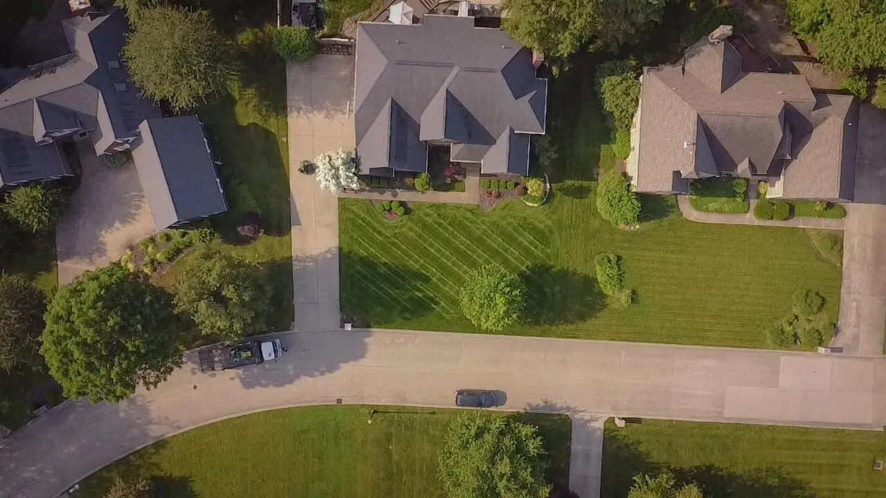 An aerial view of a striped front lawn between houses