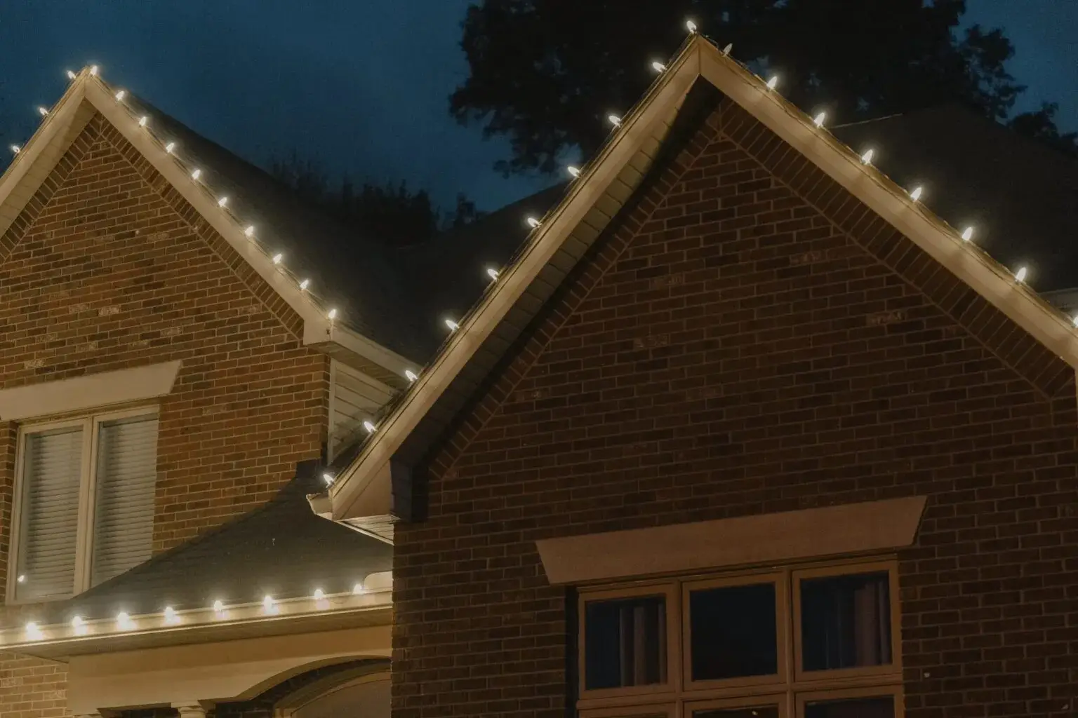 Holiday lights along the gables of a brick house