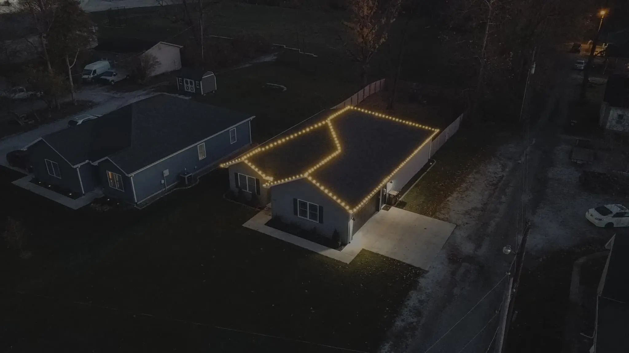 An aerial view of a house outlined in holiday lights