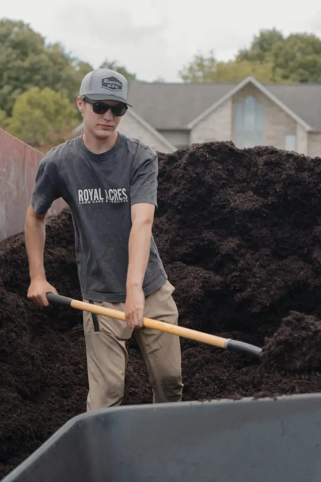 A crew member shoveling mulch into a wheelbarrow